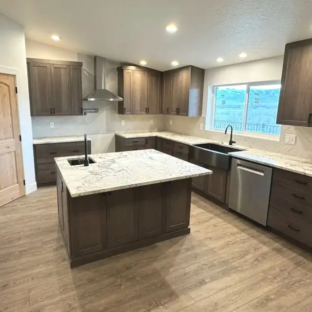 Kitchen with dark stained cabinets, granite island, stainless chimney hood and window over the sink