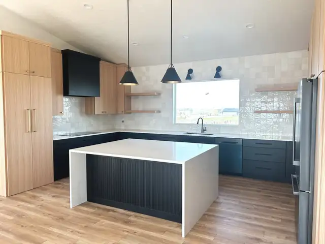 Kitchen remodel with light oak tall cabinets, navy lower cabinets, white waterfall island and black pendant lights