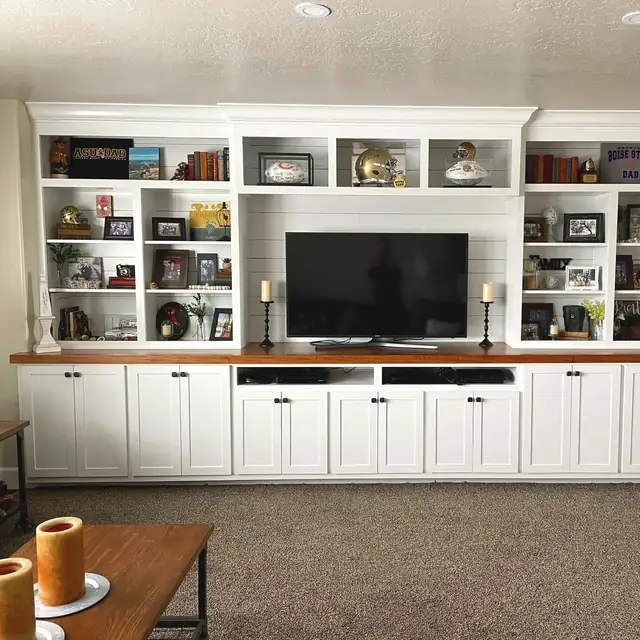 Custom white built-in media wall with open display shelves and wood countertop over base cabinets
