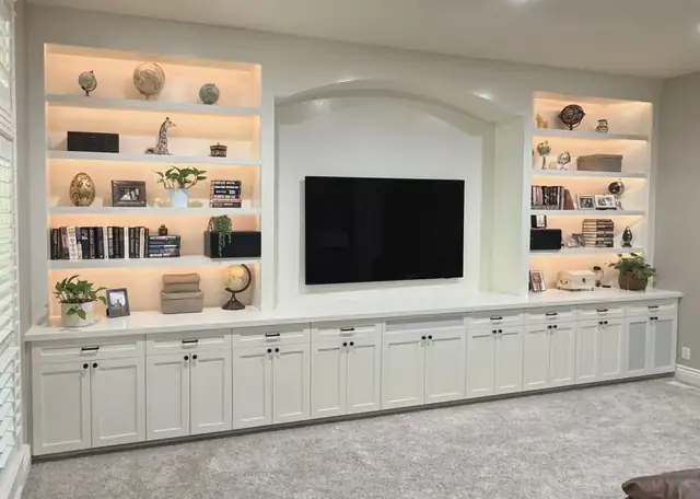 Custom white built-in entertainment wall with lighted open shelves, arched TV niche and shaker base cabinets