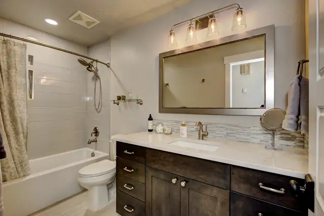 Hall bathroom with shiplap tub surround, espresso vanity, framed mirror and four-light vanity fixture