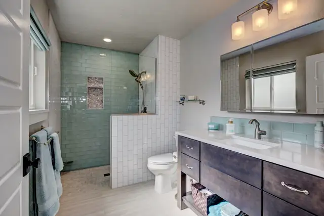 Bathroom with seafoam glass subway tile walk-in shower, white tile half wall and espresso wood vanity